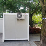 Vista frontal de dos módulos prefabricados tipo camerino instalados por Europa Prefabri para el Ayuntamiento de Pinto, con acceso independiente y acabados en blanco. En el entorno se aprecia una zona urbana destinada a actividades culturales.