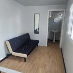 Interior de un módulo camerino equipado, mostrando el mobiliario instalado: sofá, mesa, espejo de cuerpo entero y sillas. El espacio está diseñado para ofrecer comodidad y funcionalidad a los artistas antes de una actuación.