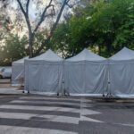 Vista frontal de dos módulos prefabricados tipo camerino instalados por Europa Prefabri para el Ayuntamiento de Pinto, con acceso independiente y acabados en blanco. En el entorno se aprecia una zona urbana destinada a actividades culturales.
